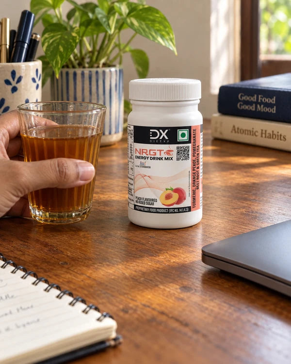 A hand holding tea at a desk beside the small NRGT Peach jar