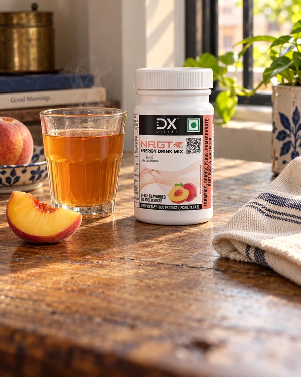 A glass of peach tea on a wooden table beside a sunlit window