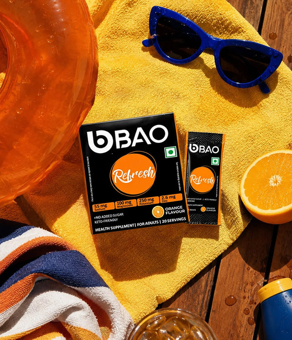 BAO Refresh box and sachet on a yellow towel beside an orange drink