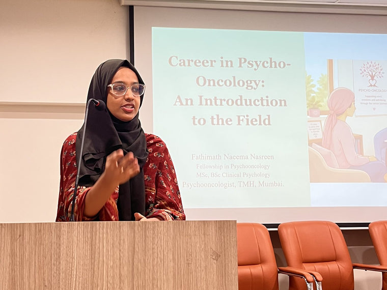 Psycho-oncologist Fathimath Naeema Nasreen speaking at a lectern beside a slide titled Career in Psycho-Oncology: An Introduction to the Field